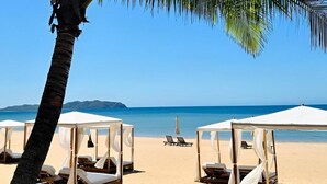 Una playa con palmeras, tumbonas y sombrillas de playa.