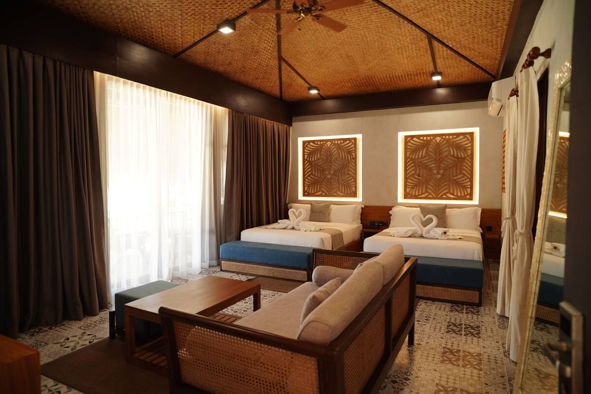 Een hotelkamer met twee bedden, een bank, een tafel en een plafondventilator.