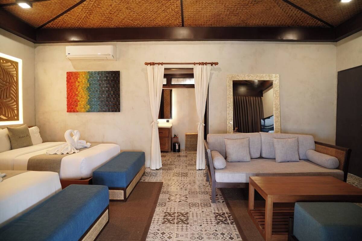Een hotelkamer met een bed, een bank, een klein tafeltje en een kamerkleed met dessin.