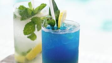 Two glasses of iced drinks with mint leaves and lemon slices, placed on a wooden surface.
