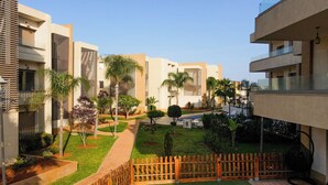 Un patio con edificios modernos, cerca de madera y abundante vegetación.