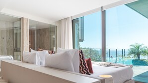 Una camera d'albergo moderna con un letto grande, un'area salotto e vista sull'oceano.