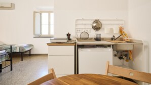 Ett kompakt kök med diskho, spis och en liten matplats med bord och stolar.