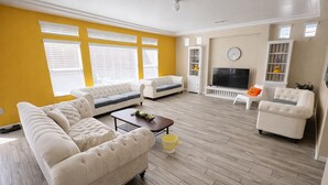 Una sala de estar con un sofá, sillones, una mesa de centro y un televisor.