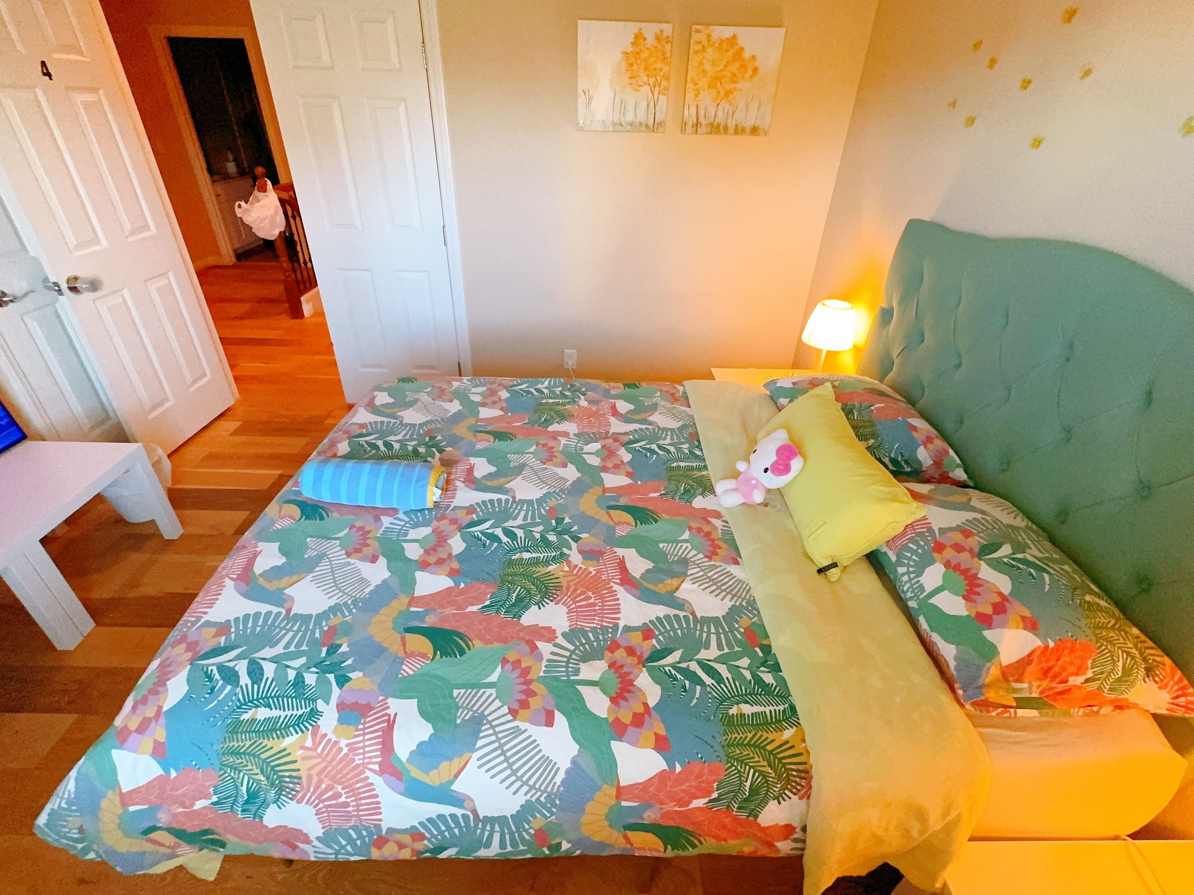 A bedroom with a bed, a bedside table, a lamp, and a door.