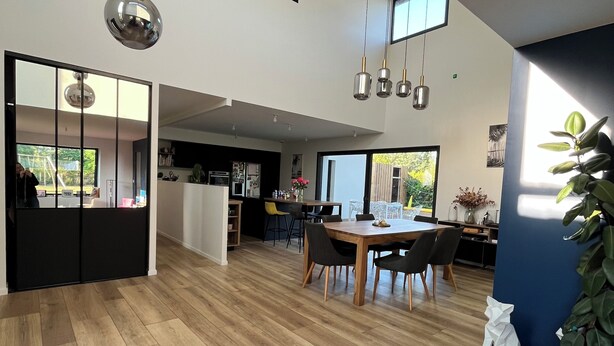 A spacious living area with a high ceiling, wooden flooring, a dining table with chairs, and a kitchen in the background. - Villa with pool Pessac between Bordeaux and Bassin d'Arcachon (Pessac)