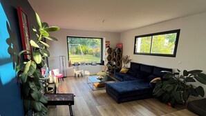 A modern living room with a blue sofa, a coffee table, and a large window offering a view of the outdoors. - Villa with pool Pessac between Bordeaux and Bassin d'Arcachon (Pessac)