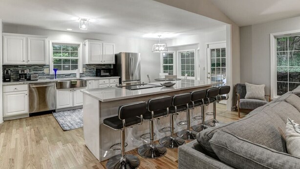 A modern kitchen with white cabinets, stainless steel appliances, and a central island with bar stools.