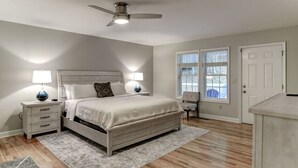 A bedroom with a bed, nightstands, a ceiling fan, and a window with blinds.