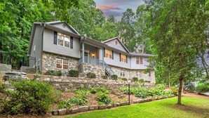 A two-story house with a stone foundation and a stone retaining wall.