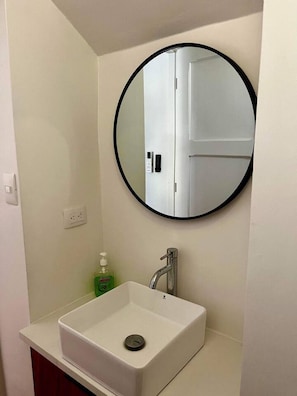 A bathroom with a white sink, a round mirror, and a green soap dispenser. - Beautiful Dolce Vita Retreat (Sardinal de Carrillo)