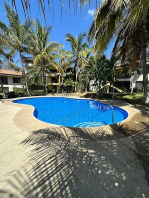 A swimming pool surrounded by palm trees and a building with a yellow facade. - Beautiful Dolce Vita Retreat (Sardinal de Carrillo)