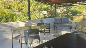 Eine Terrasse im Freien mit Gasherd, Sitzgelegenheit und Blick auf Grün.