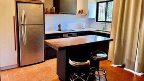 Eine moderne Küche mit einem Edelstahl-Kühlschrank, einer Holz-Kochinsel mit Barhocker und einem Fenster mit Vorhängen.