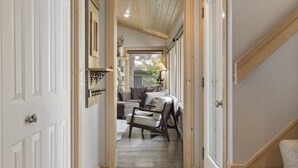 A narrow hallway with a wooden ceiling, a sofa, and a chair in the background. - Attitude Adjustment on Glen Lake (Glen Arbor)