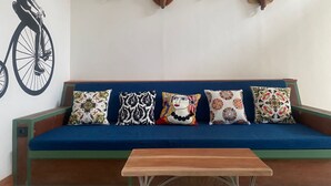 A room with a blue sofa, colorful pillows, and four mounted animal heads on the wall.
