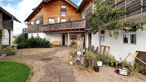 Una casa de madera con un balcón, plantas en macetas y un camino de piedra.