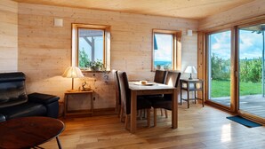 Un interior de madera con una mesa de comedor, sillas, un sofá y una lámpara.