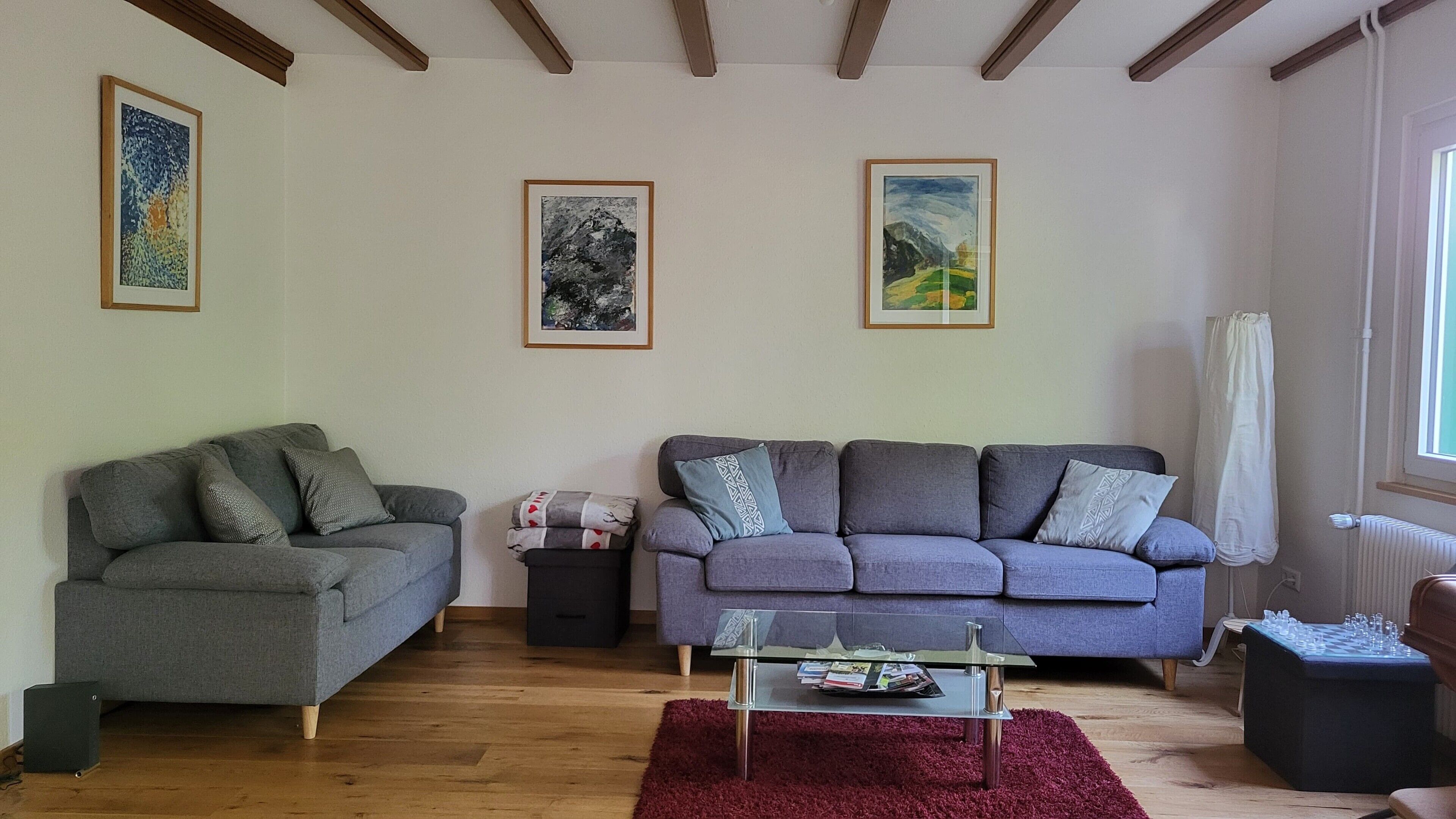 Un salon avec deux canapés, une table basse et des œuvres d’art encadrées accrochées aux murs.