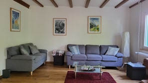 Un salon avec deux canapés, une table basse et des œuvres d’art encadrées accrochées aux murs.