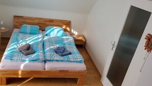 A bedroom with a wooden bed, two bedside tables, a radiator, and a wall-mounted clock.