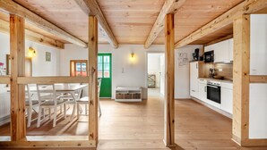 A spacious kitchen with wooden beams, white cabinets, and a dining area with a table and chairs. - Apartment 'Hochwald' with Mountain View and Wi-Fi (Bertsdorf-Hörnitz)