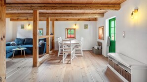 A room with a wooden ceiling, a dining table with chairs, a sofa, and a green door. - Apartment 'Hochwald' with Mountain View and Wi-Fi (Bertsdorf-Hörnitz)