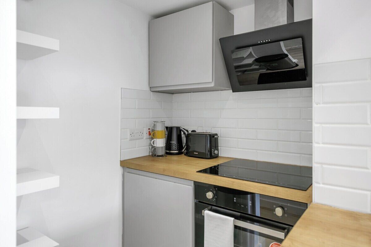 A compact kitchen with a built-in oven, a microwave, and a coffee maker on the countertop.