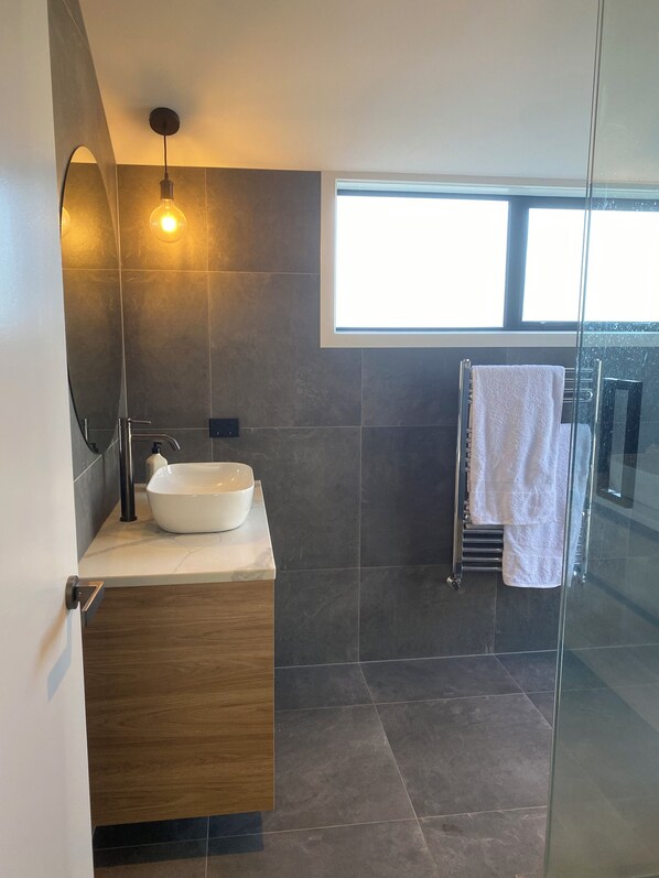 A modern bathroom with a large sink, a glass shower enclosure, and a towel rack. - Modern Retreat in Lynmore, Rotorua (Rotorua)