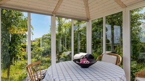 A conservatory with a checkered tablecloth, wicker furniture, and a view of lush greenery. - "Marret" - 275m from the sea by Interhome (Hejls)