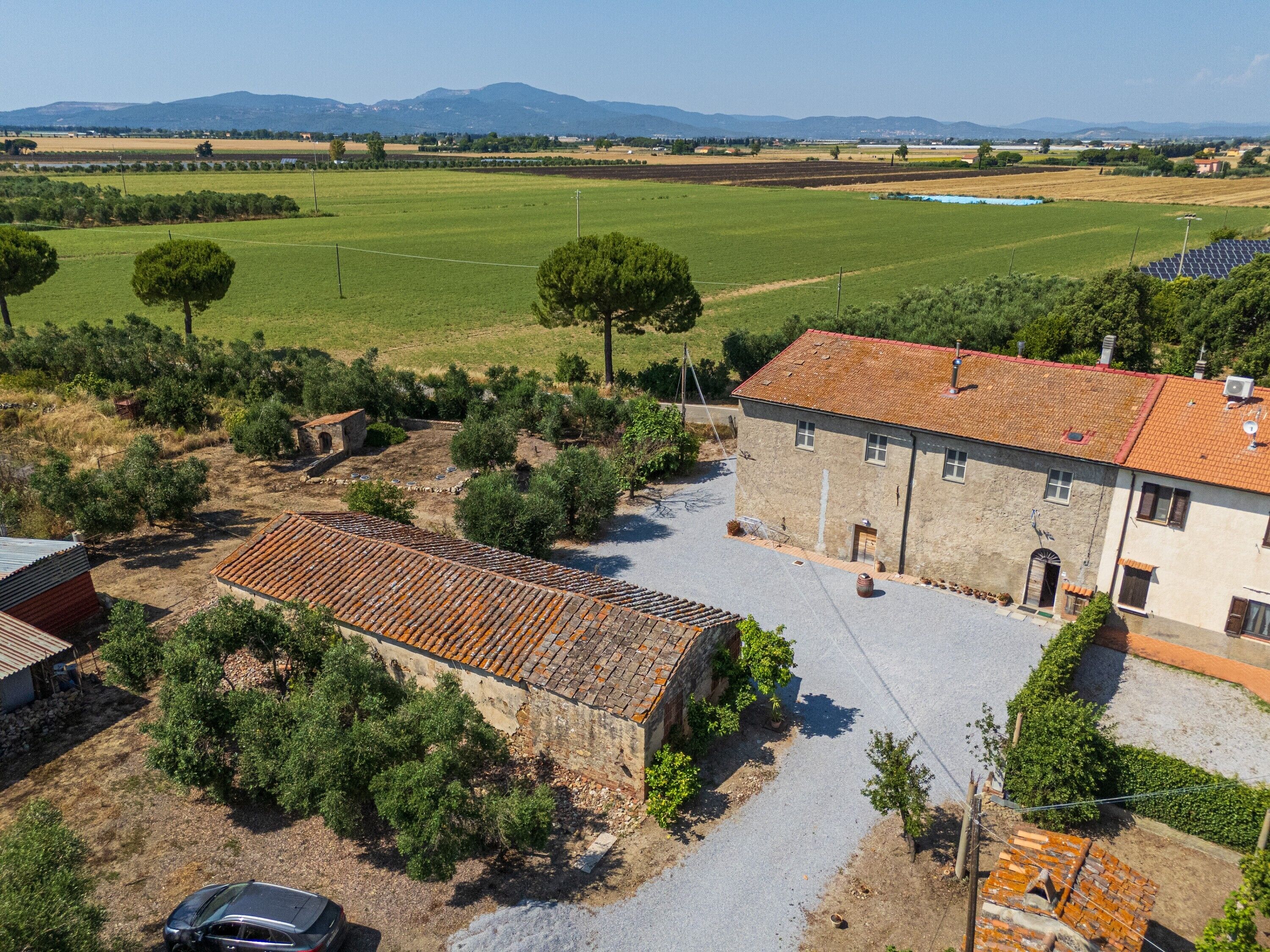 A rural property with a stone building, a paved driveway, and a car parked in front.