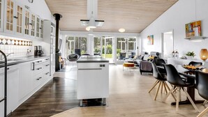 A modern kitchen with white cabinets, a central island, and a dining area with black chairs and a wooden table.