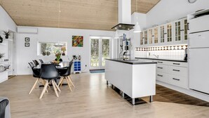 A modern kitchen with white cabinetry, a central island, and a dining area with a table and chairs.