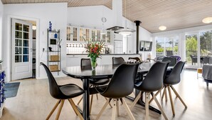 A modern kitchen with white cabinets, a central island, and a dining area with a round table and black chairs.