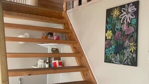 A wooden staircase with a white wall and a floral painting.