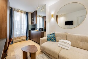 Una sala de estar moderna con un sofá, una mesa de centro, un televisor y un área de cocina con un microondas.
