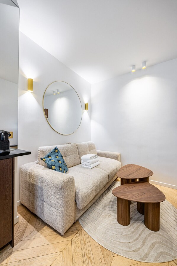 Una sala de estar moderna y minimalista con un sofá, un espejo redondo y una mesa de centro de madera.