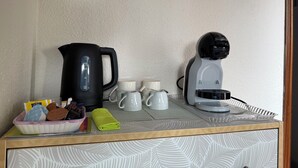 Eine Küchenzeile mit Kaffeemaschine, Wasserkocher und Tassen auf einer Arbeitsplatte.