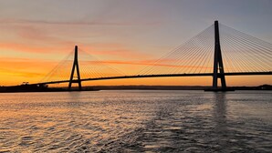 Eine Hängebrücke im Abendlicht mit Wasser darunter.