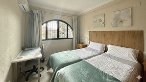 Ein Schlafzimmer mit zwei Betten, einem Schreibtisch und einem Fenster mit Vorhängen.