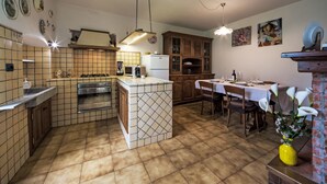 A kitchen with a central island, wooden cabinets, and a dining area with a table set for two. - Casa Brezza del Gabberi by Interhome (Camaiore)