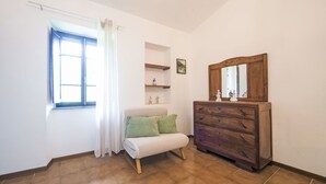 A room with a window, a bed, a dresser, and a shelf with decorative items. - Casa Brezza del Gabberi by Interhome (Camaiore)