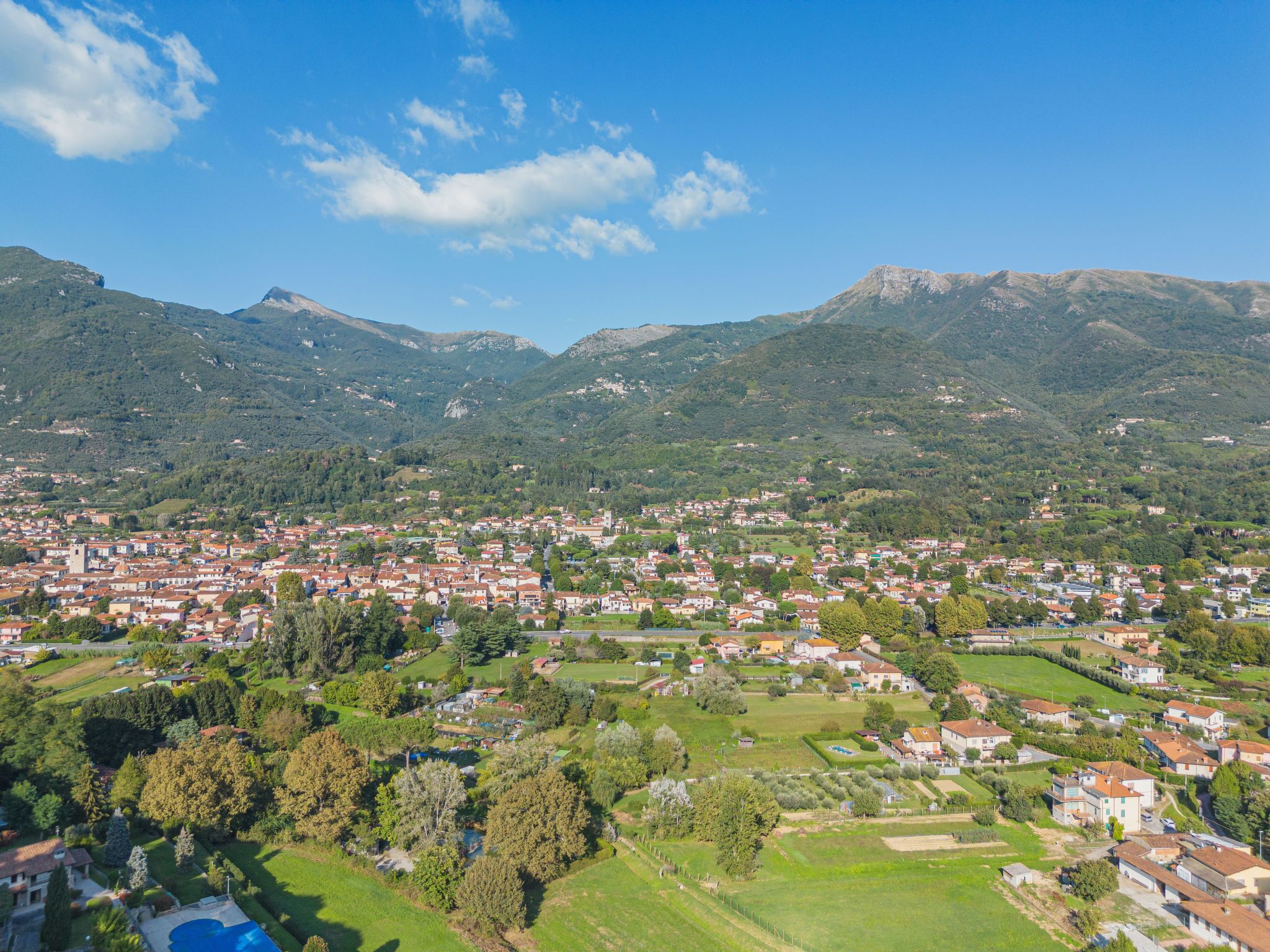 Un pueblo enclavado en un valle, con montañas al fondo, que presenta una combinación de edificios residenciales y zonas verdes.