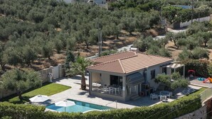 Ein modernes Haus mit Ziegeldach, Swimmingpool und einer Terrassenfläche.