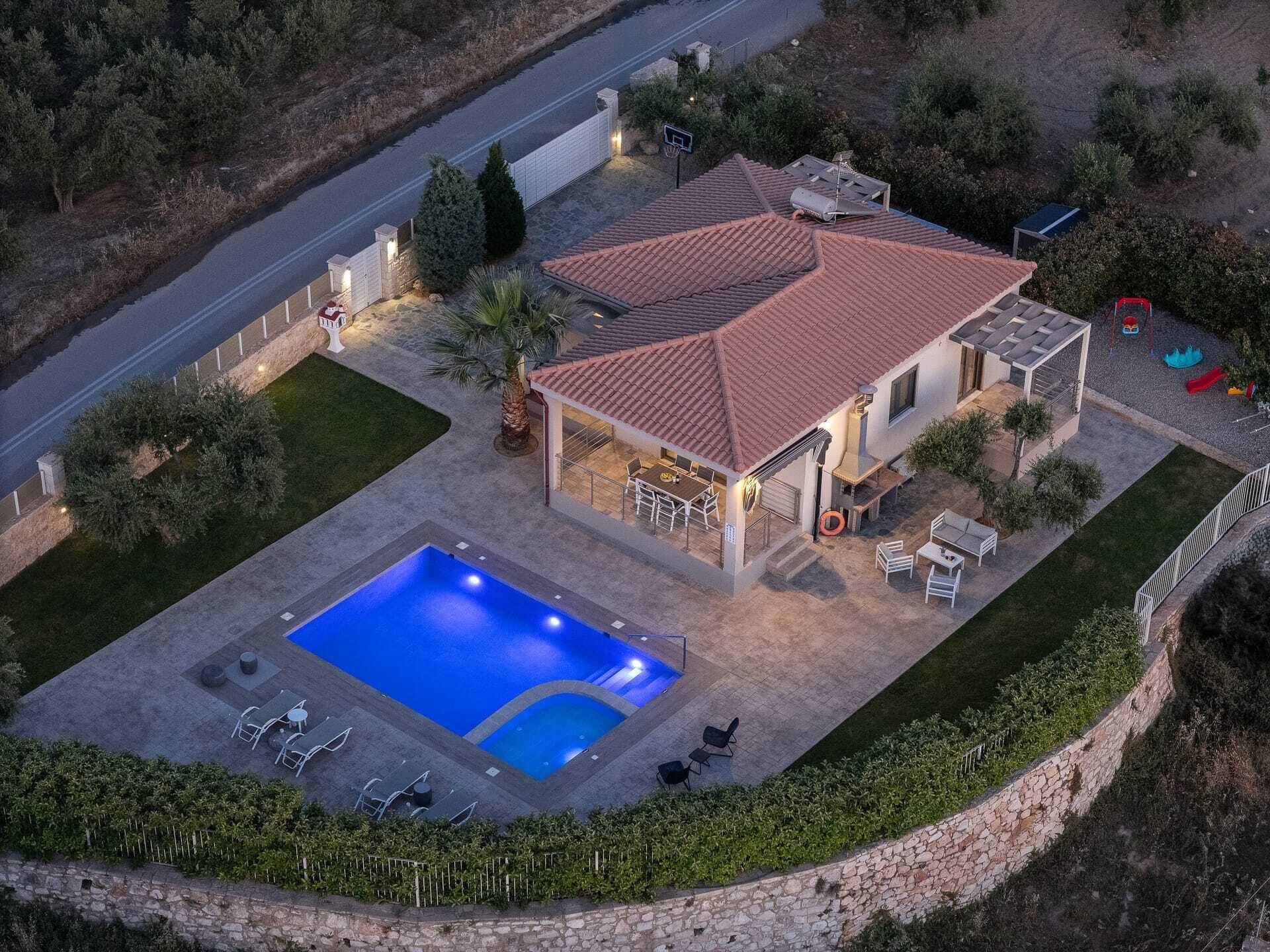 A house with a swimming pool, patio furniture, and a fenced yard.