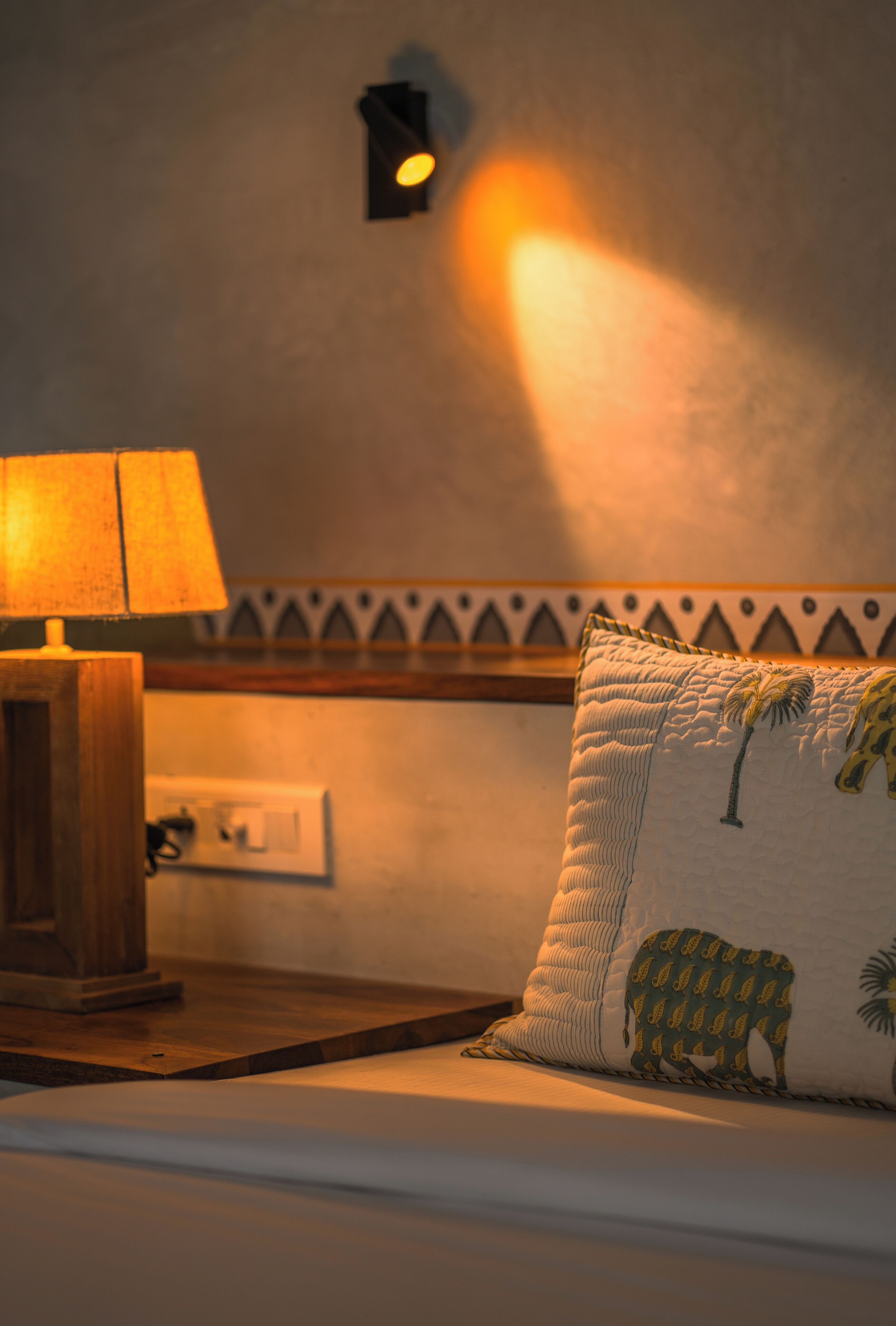 A bedroom with a bed, a nightstand, a lamp, and a wall-mounted light fixture.
