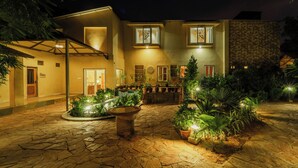 A well-lit courtyard with a stone floor, potted plants, and a central water feature. - Tehla Bagh (Talab)