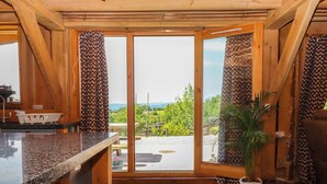 A wooden interior with a kitchen counter, a dining area, and a large sliding glass door leading to an outdoor patio. - Pucklechurch (Newton Abbot)