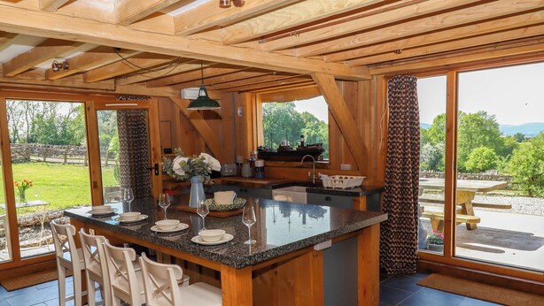 A spacious kitchen with a large island, bar stools, and a view of the outdoors. - Pucklechurch (Newton Abbot)