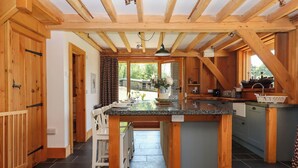 A kitchen with a central island, wooden beams, and a view of the outdoors. - Pucklechurch (Newton Abbot)